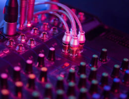 Sound mixer control panel on dark light background in audio control room.