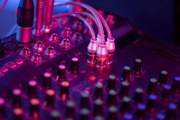 Sound mixer control panel on dark light background in audio control room.
